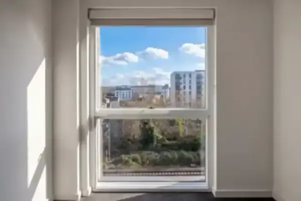 A bright interior view of secondary glazing installed near a busy transit line, showing a quiet sanctuary
