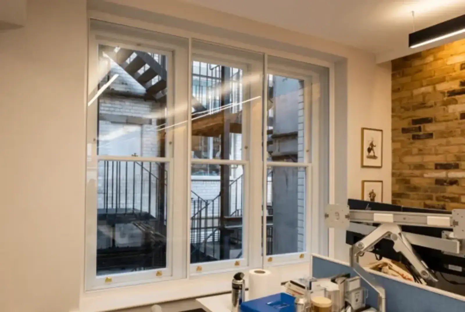 White secondary glazing frames fitted inside a workspace with an exposed brick wall